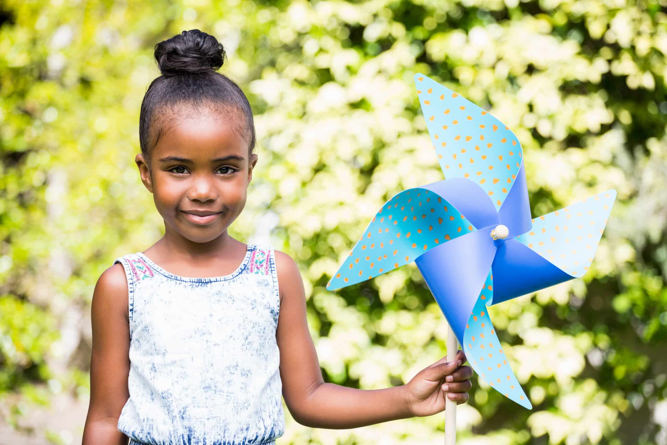 Little girl holding a pinwheel at park on a sunny day